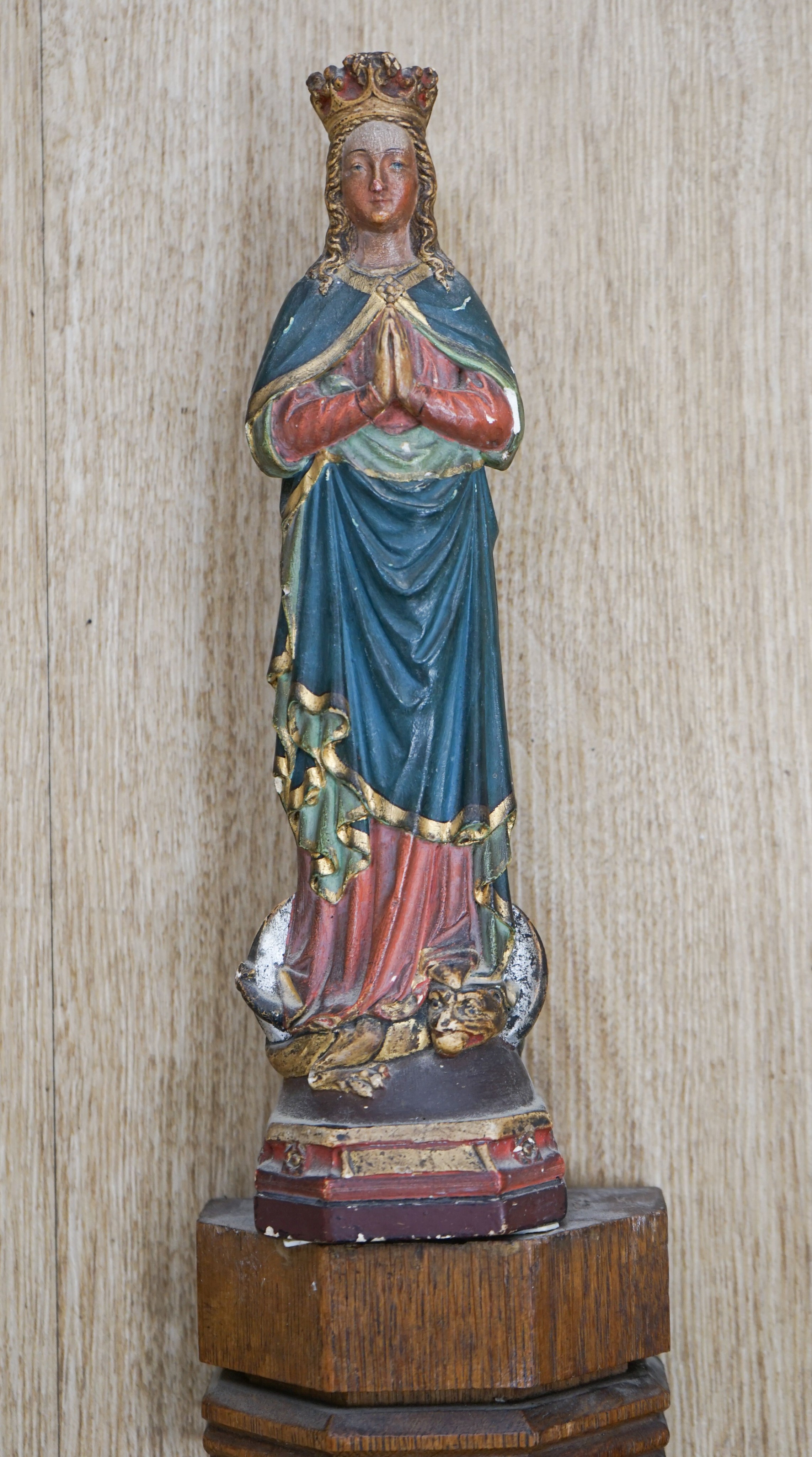 An early hand bell and a religious figure on an oak pilaster 65cm